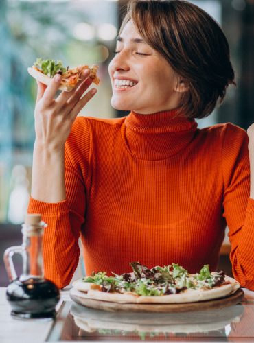 Young pretty woman eating pizza at pizza bar